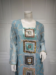 Detail of light blue long sleeve dress featuring colorful sequins and floral embroidery