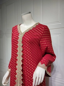 Detail eines roten V-Ausschnitt-Kaftans mit Goldfolienmustern und floraler Spitzenstickerei