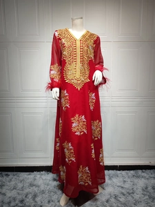 Détail du caftan rouge avec broderie florale dorée et poignets en plumes d'autruche