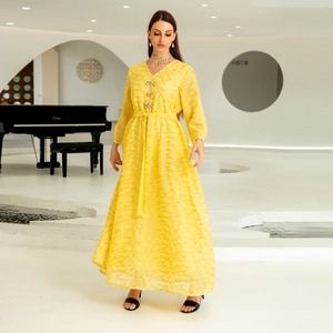 Detail of a yellow mesh dress with gold embroidery and gemstone buckle on the waistline