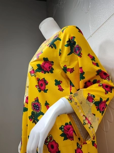 Detailed close-up of yellow floral satin fabric with gold sequin embroidery on sleeves