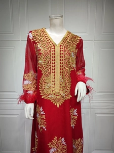 Détail de la robe en mousseline rouge avec broderie dorée et poignets en plumes d'autruche