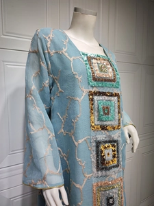 Detail of light blue sequined maxi dress with intricate embroidery and long sleeves