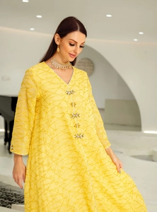 Detail of elegant yellow V-neck maxi dress with gold textures and floral crystal buttons