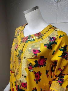 Detail of yellow dress with gold embroidery and floral print on silk texture fabric