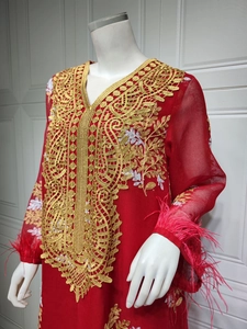 Détail d'un caftan rouge avec broderie dorée et plumes aux poignets des manches