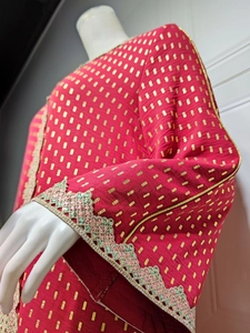 Detailansicht eines roten Kleides mit goldenen Geometrie-Prints und Paillettenmanschetten