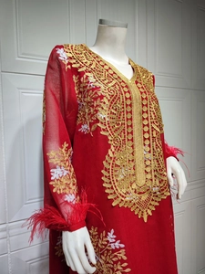 Détail d'un caftan rouge avec broderies de dentelle dorée et poignets en plumes