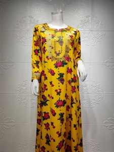 Detailed view of gold embroidery and floral patterns on a yellow kaftan dress