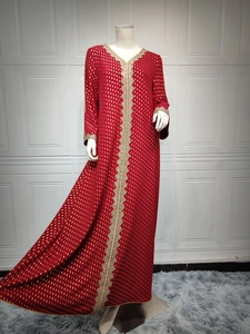 Detail eines roten Abaya-Kleides mit goldenen Punkten und gelber Spitzenverzierung