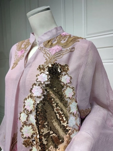 Detaillierte Nahaufnahme aufwendiger Gold- und Weiß-Paillettenstickerei auf rosa Abendkleid.