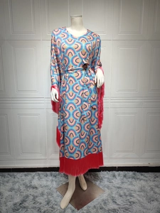 Detail of vibrant geometric kaftan dress featuring red tassel fringe and waist tie belt