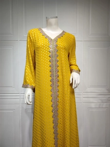 Detail von gelbem Kaftan-Kleid mit bunter Stickerei und Goldpailletten am Ausschnitt