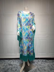 Détail d'une robe caftan en satin imprimé avec franges vert émeraude aux manches et l'ourlet