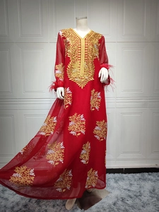 Détails de broderie florale dorée et paillettes sur une robe caftan rouge élégante