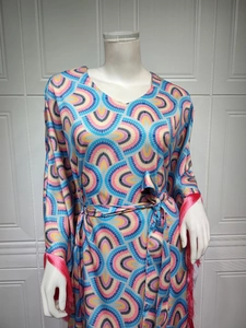 Detail of V-neck dress featuring geometric patterns and red fringe tassels on the cuffs