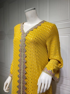 Detail des V-Ausschnitts mit Stickerei und Goldfolienmuster auf gelbem Kaftan-Kleid
