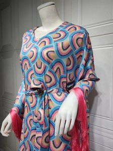 Detail of vibrant rainbow geometric dress featuring long fuchsia fringe on sleeves