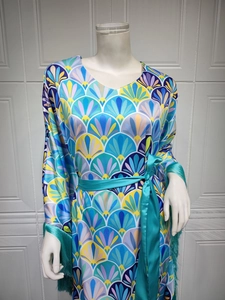 Détail d'une robe bohème à imprimé géométrique avec poignets à pompons et ceinture en satin