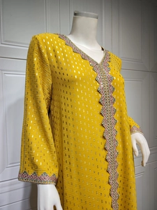 Detailansicht der Goldfolienmuster und bunten Wellenstickerei an gelbem Kaftan-Kleid