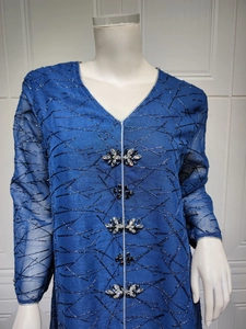 Close-up of sparkling rhinestone buttons and silver embroidery on navy mesh dress