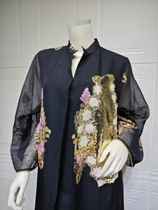 Detailansicht eines eleganten schwarzen Abendkleids mit goldenen Pailletten und Blumenstickerei.