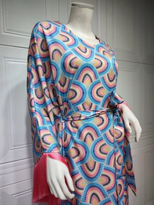 Detail of light blue dress with geometric print, fringe cuffs and matching waist belt