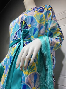 Détail des poignets à franges et de la ceinture en soie sur cette robe en satin