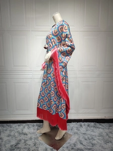 Detailed side view of long caftan dress featuring geometric prints and red fringe trim