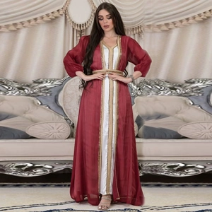 Detail of red kaftan with gold embroidery trim and lantern sleeves in luxurious fabric