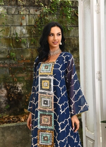 Macro view of blue kaftan dress showing geometric sequin embroidery and white branch patterns