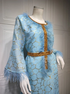 Detail des hellblauen Abaya-Kleides mit Goldmuster, blauen Federn und Perlenbesatz