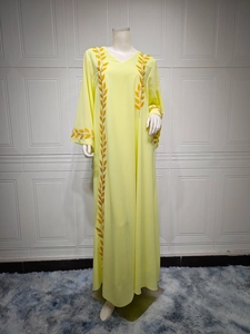 Close-up detail of the orange leaf embroidery on the neckline of a long yellow chiffon abaya