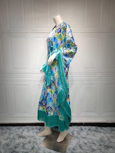 Détail de robe de soirée en satin avec pompons turquoise et motifs géométriques colorés