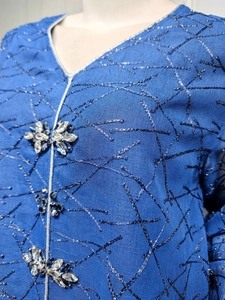 Detail of blue mesh dress featuring silver embroidery and crystal beaded floral ornaments