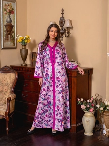 Detail of floral kaftan dress showing V-neckline with decorative buttons and velvet trim