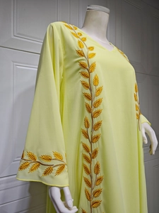 Detail of golden leaf embroidery on the neckline and sleeves of a yellow chiffon kaftan