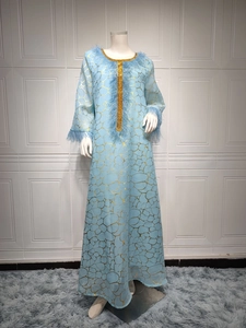 Detail eines hellblauen Kaftans mit Goldmustern, Federbündchen und Paillettenbesatz