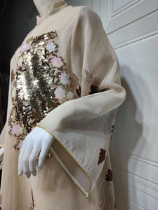 Detailansicht eines beigen Abendkleids mit goldener Paillettenstickerei und floralen Mustern
