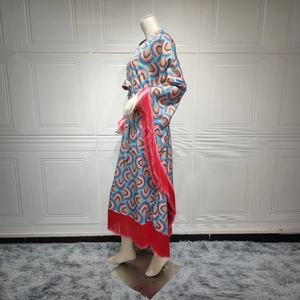 Women's long maxi dress with colorful geometric prints and red fringe trim on wide sleeves
