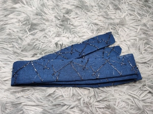 Detailed close-up of dark blue mesh embroidery with silver geometric patterns and hand beads