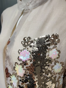 Nahaufnahme der komplizierten Pailletten-Stickerei auf einem beigen Abendkleid detail