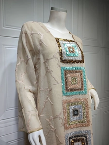 Close-up of beige sequin dress featuring branch embroidery and colorful square patches