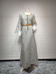 Detail eines hellblauen Abaya-Kleides mit goldenen Rissmustern und Federbesatz-Akzenten