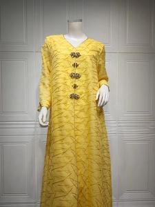 Detail of yellow kaftan dress featuring mesh embroidery and ornate rhinestone clusters