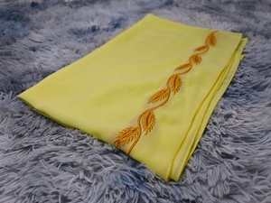 Detail of yellow chiffon hijab featuring gold leaf embroidery on a grey plush background