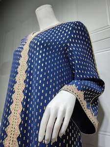 Detail eines navyblauen Kaftans mit Goldpunktmuster und buntem Häkelspitzenbesatz