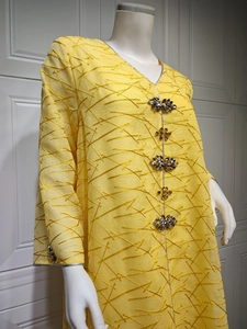 Detailed view of yellow embroidered kaftan with floral jewel buttons and silver trim