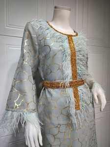 Detail des hellblauen Kleides mit goldenem Netzdruck und luxuriösem Federbesatz