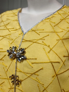 Detail of yellow mesh dress with intricate embroidery and handmade crystal beaded V-neckline